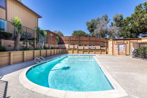 a swimming pool with a fence and a house with a resort style pool