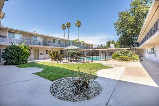 a courtyard with a pool and a building with palm trees