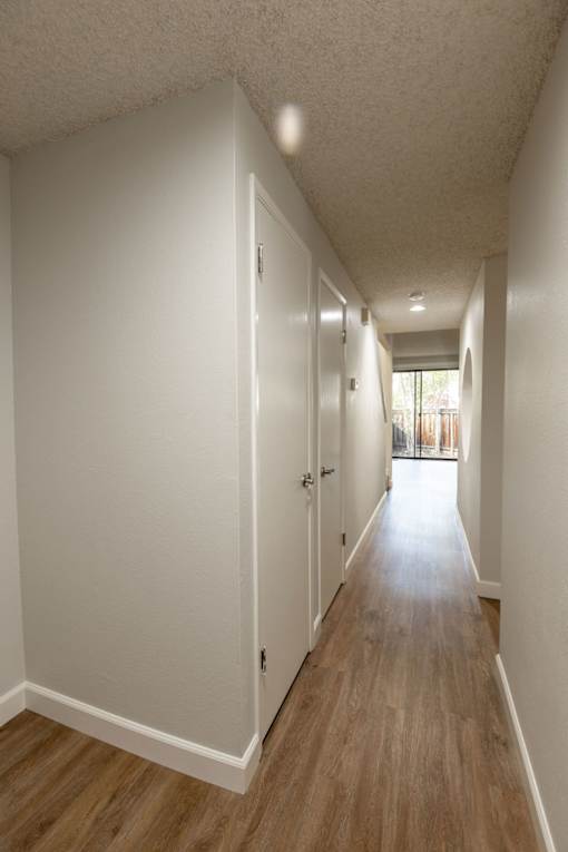 an empty hallway with white walls and wood floors