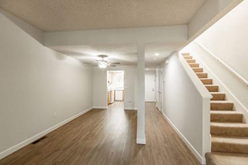 an empty living room with stairs and a ceiling fan