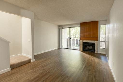 an empty living room with a fireplace and wooden floors