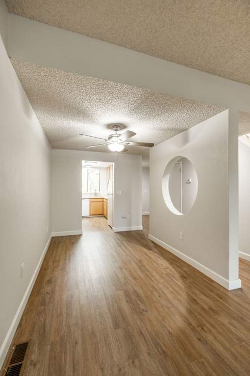 an empty living room with a ceiling fan and wood flooring