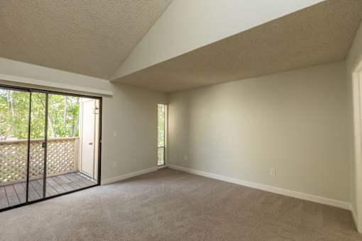 an empty living room with a sliding glass door to a balcony