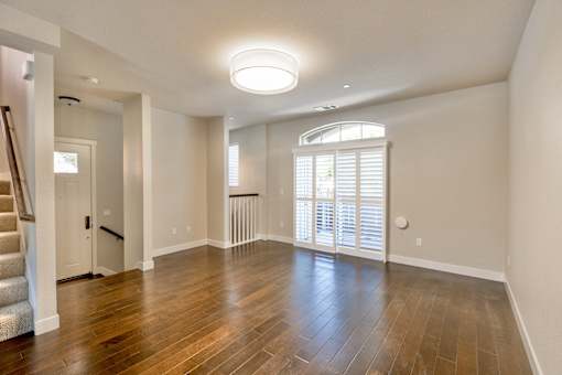 an empty living room with wood floors and a large window
