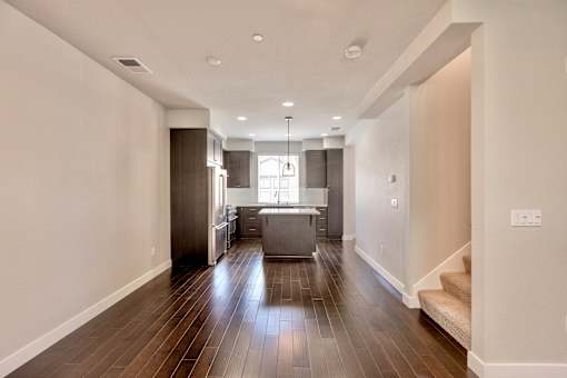 a living room and kitchen with wood floors and white walls
