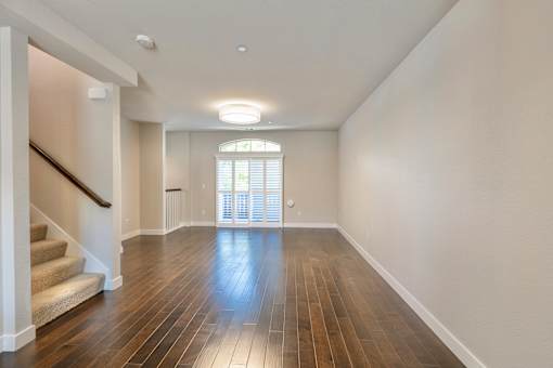 an empty living room with hardwood flooring and a large window and stairs