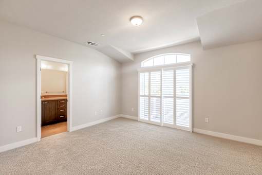 an empty living room with a large window and a door to a bathroom