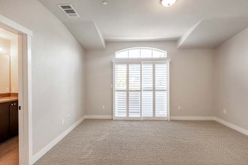 an empty living room with a large window and blinds