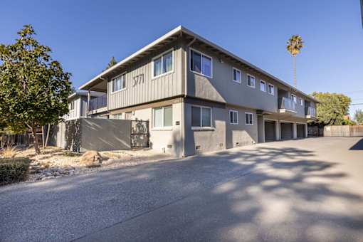 A grey two-story house with a driveway in front.