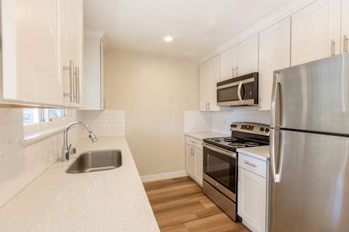 A kitchen with a stainless steel refrigerator, oven, and sink.