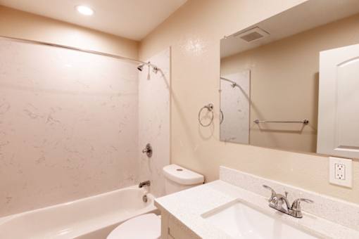 A bathroom with a white tub, sink, and toilet.