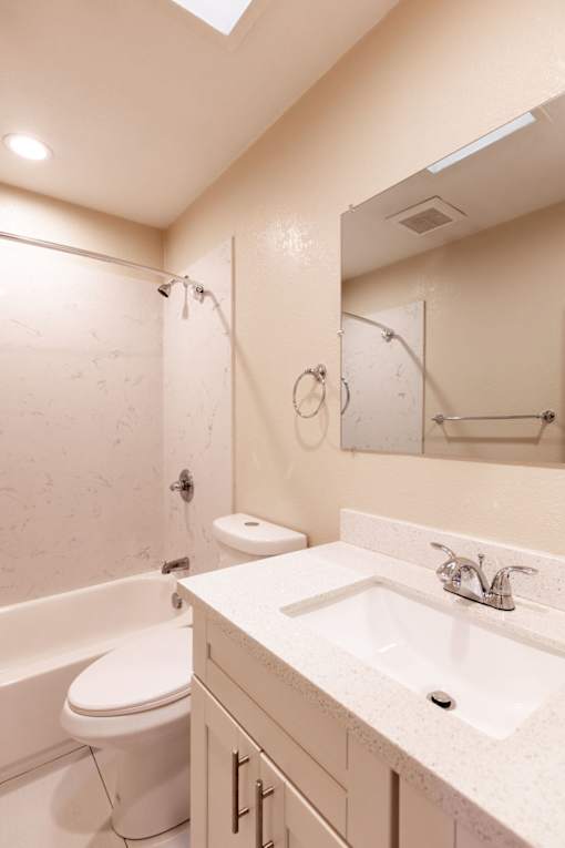 A white bathroom with a toilet, sink, and bathtub.