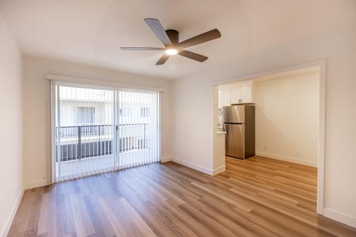 A room with a ceiling fan and a refrigerator.
