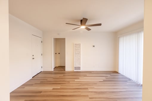 A room with a ceiling fan and wooden flooring.