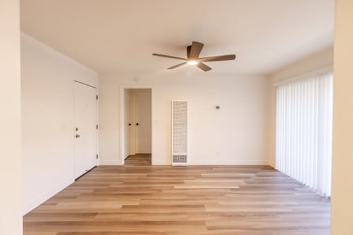 A room with a ceiling fan and wooden flooring.