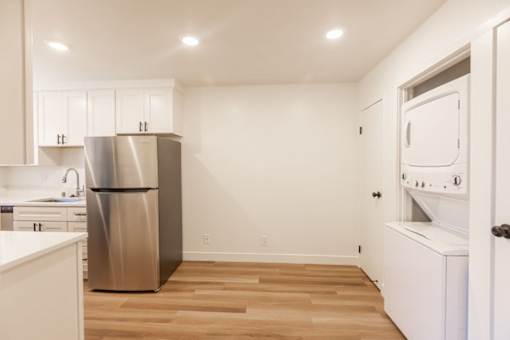A kitchen with a stainless steel refrigerator and wooden flooring.