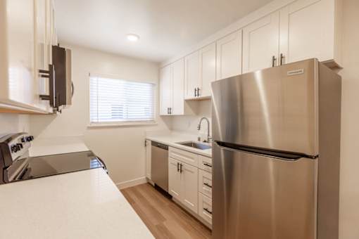 A modern kitchen with a stainless steel refrigerator and white countertops.