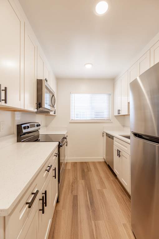A kitchen with wooden cabinets and a stainless steel refrigerator.