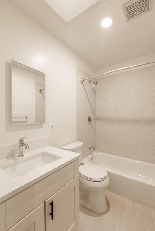 A white bathroom with a toilet, sink, and bathtub.