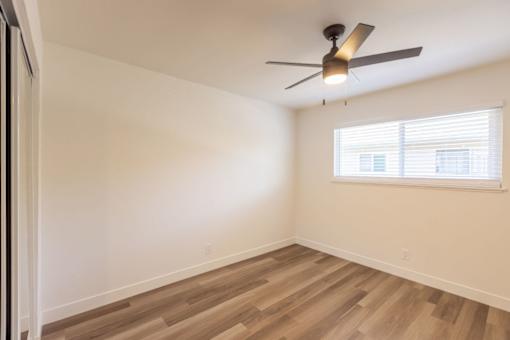 A room with a ceiling fan and a window with blinds.
