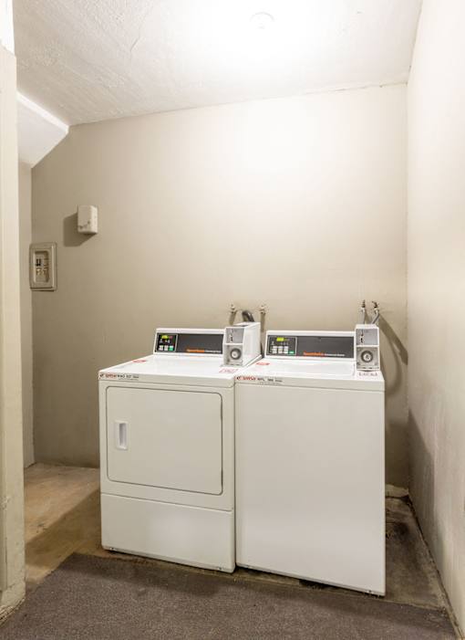 Two identical white machines with digital displays are in a room.