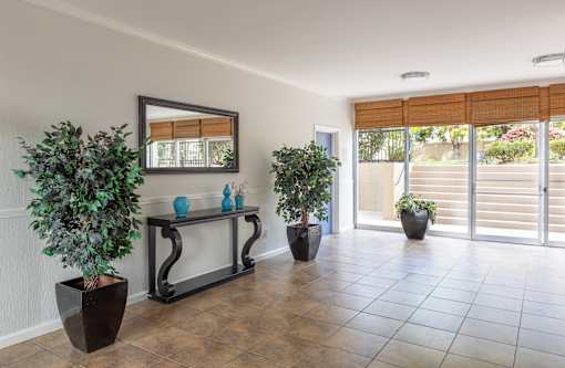 A room with a mirror, a bench, and potted plants.