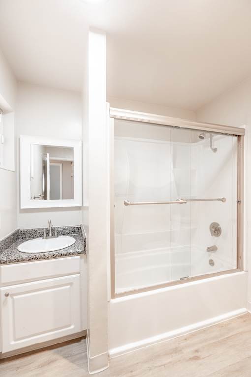 A bathroom with a sink, mirror, and shower.