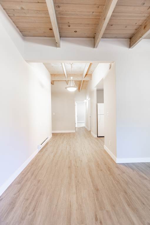 A long, empty hallway with wooden floors and white walls.