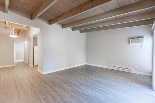 A room with wooden floors and a white wall with a window.