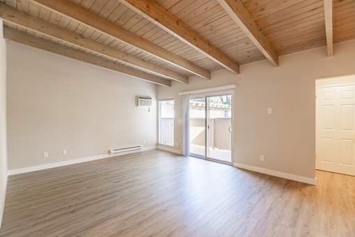 A room with wooden floors and a high ceiling with exposed beams.