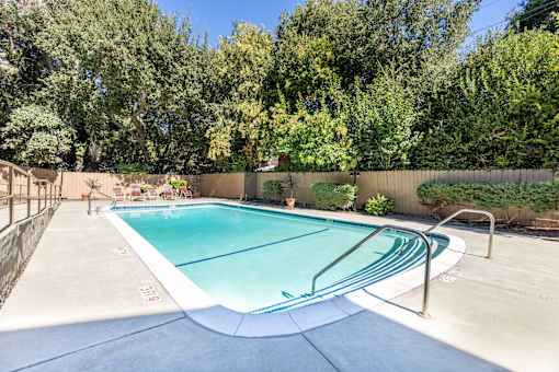 A rectangular pool with a white border and a metal ladder on the side.
