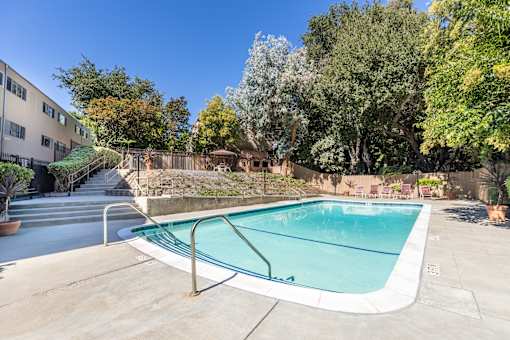A small pool surrounded by trees and a building.