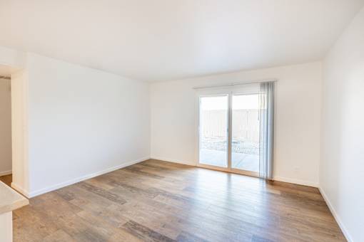 A room with wooden flooring and a sliding glass door.