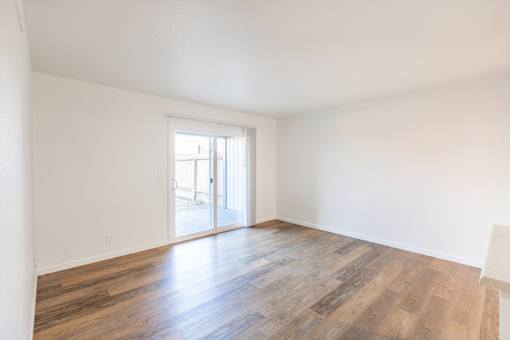A room with a wooden floor and a sliding glass door.