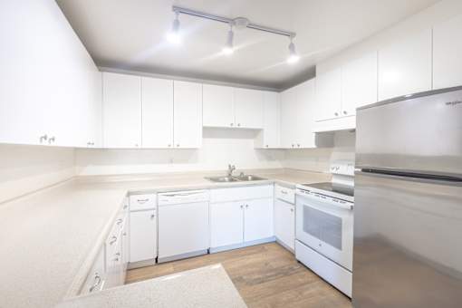 A modern kitchen with white cabinets and stainless steel appliances.