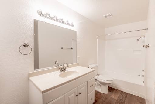 A white bathroom with a sink, toilet, and shower.