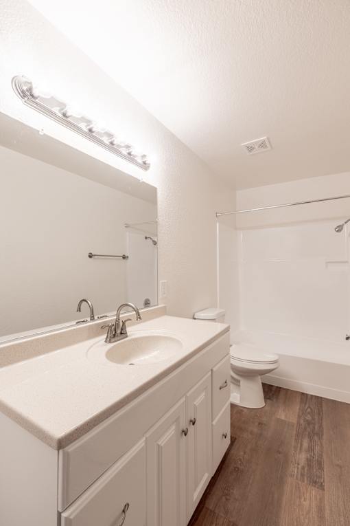 A white bathroom with a sink, toilet, and mirror.