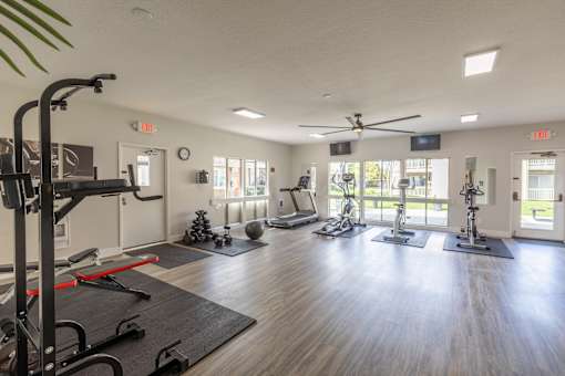 A gym with a variety of equipment including treadmills, stationary bikes, and weight machines.
