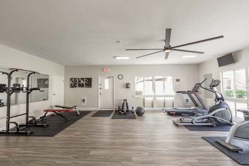 A spacious gym with a variety of equipment and a ceiling fan.