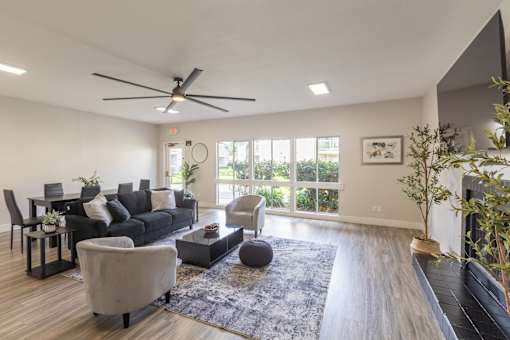 A modern living room with a black sofa, a grey armchair, a coffee table, and a ceiling fan.