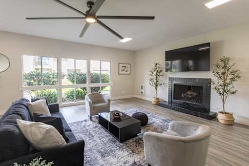 A living room with a black couch, a fireplace, and a ceiling fan.