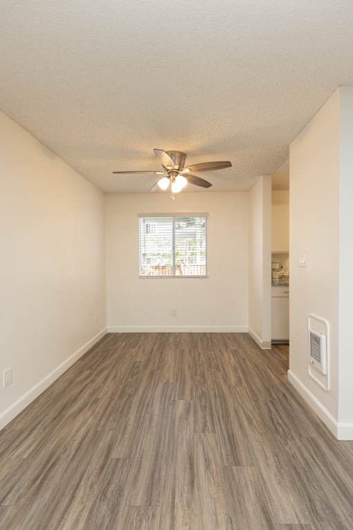 A room with a ceiling fan and a window with blinds.