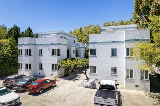 the apartment buildings are painted white and blue with cars parked in front of them