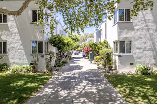 a sidewalk in front of some white buildings and trees