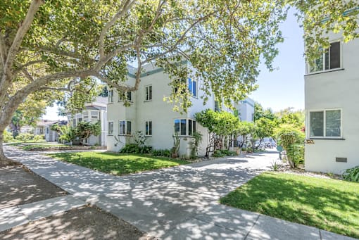 a white apartment building with a sidewalk and trees