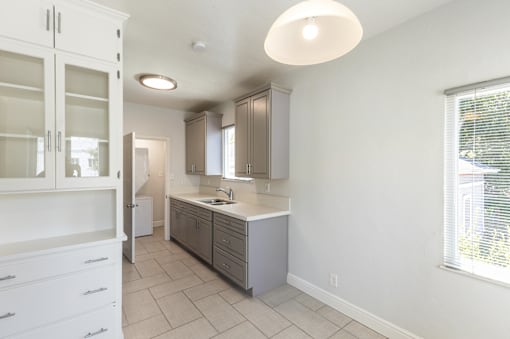 an empty kitchen with white cabinets and a window