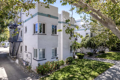 a white building with a yard and trees in front of it