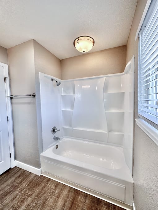 a bathroom with a white bathtub and a window