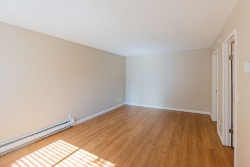 an empty room with wooden floors and white walls