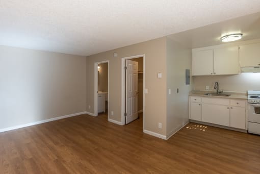 an empty kitchen and living room with a wooden floor